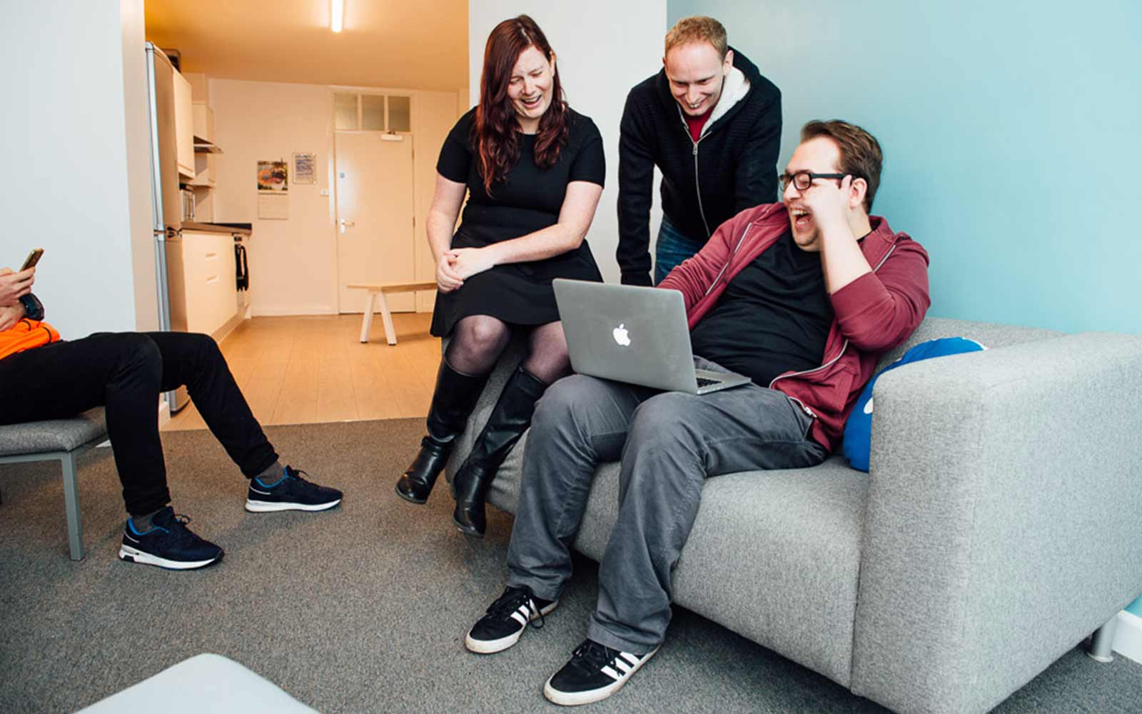 Students sitting around a laptop in the Grange communal area.